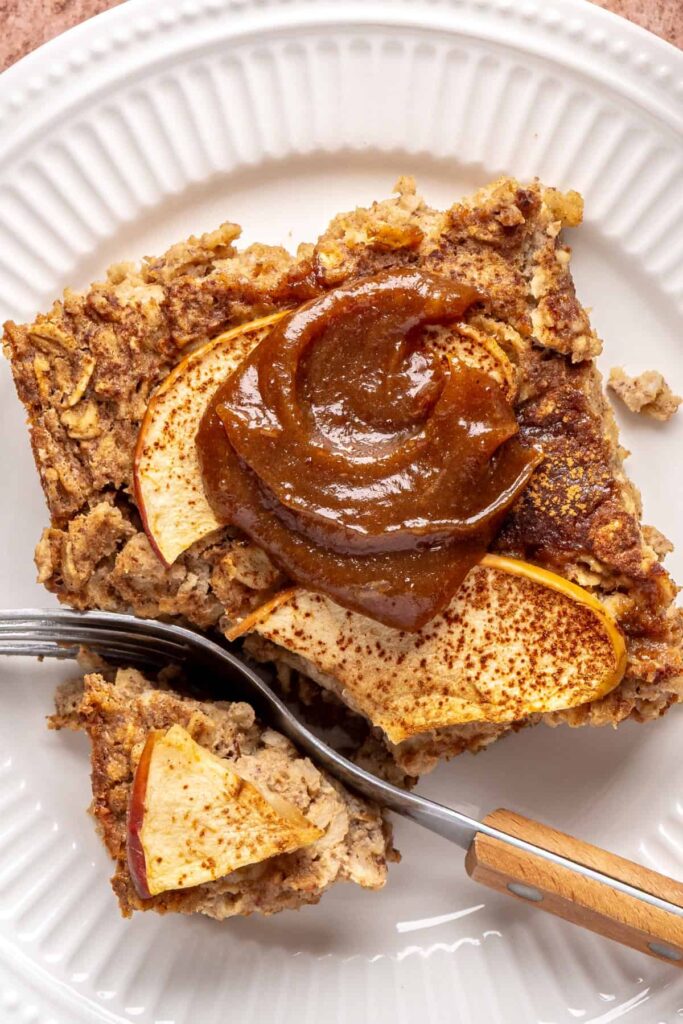 close up of a slice of baked apple oatmeal with caramel on a white plate, cozy breakfast