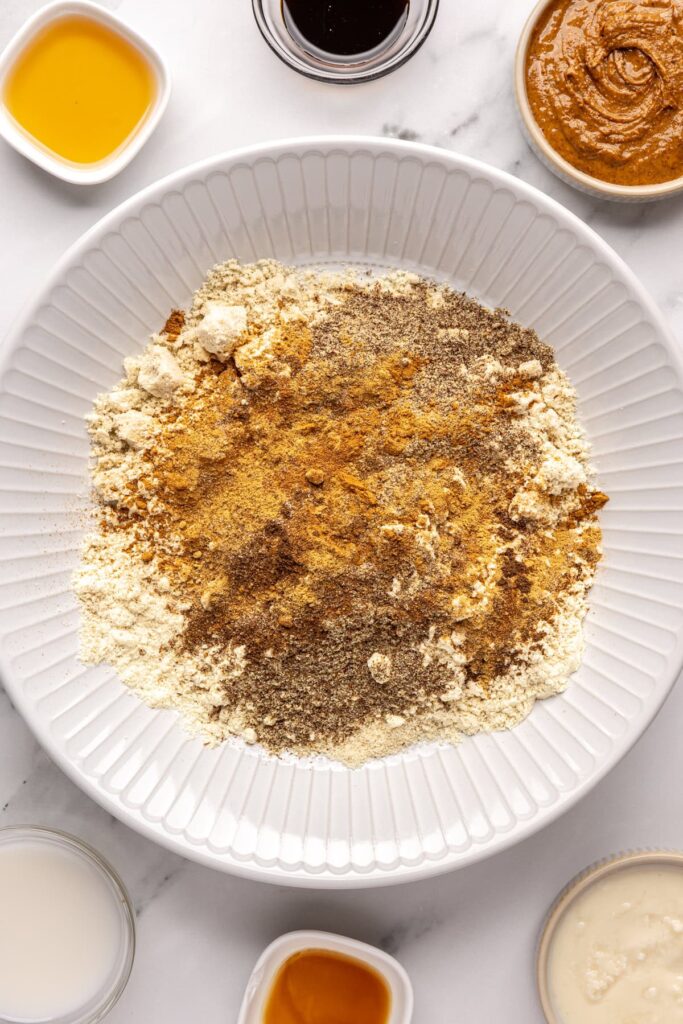 Dry ingredients for gingerbread protein balls: almond flour, protein powder, flaxseed, and warm spices in a mixing bowl
