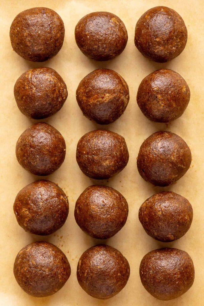 Chilled gingerbread protein balls on parchment paper, ready to drizzle with coconut butter