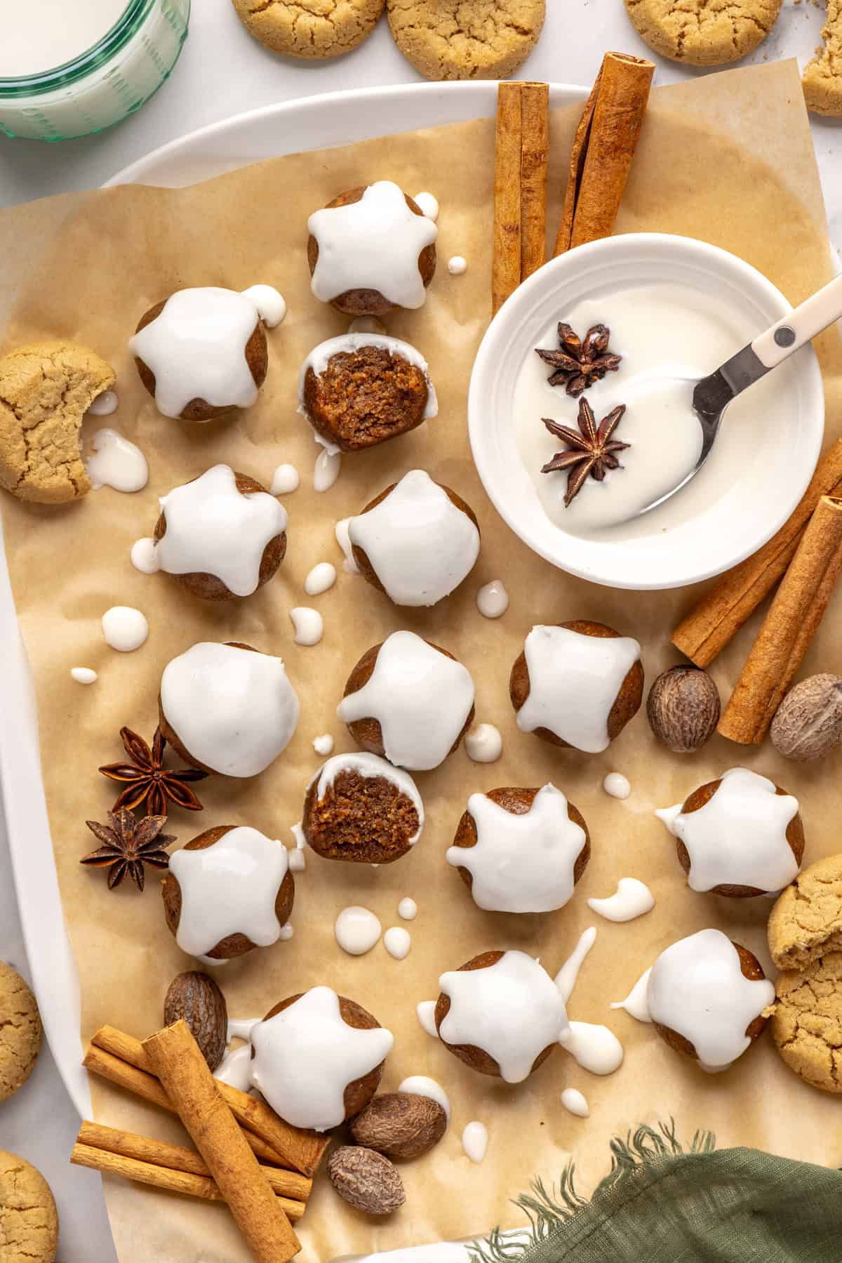 Finished gingerbread protein balls drizzled with coconut butter, styled on a baking sheet with cloves and ginger cookies, ready to enjoy