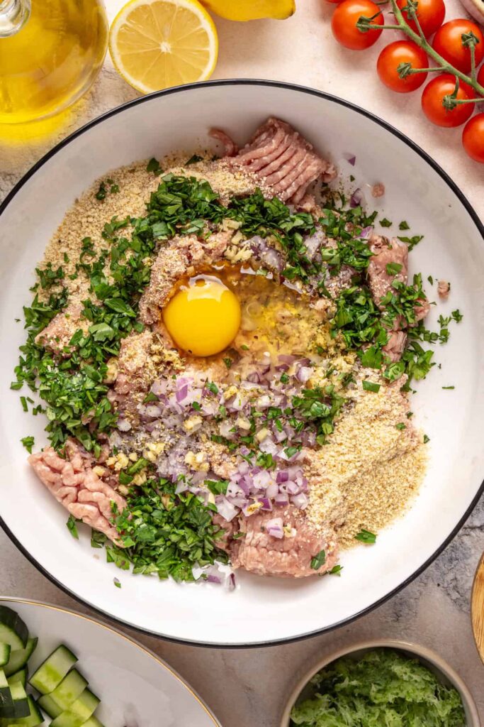 Ground turkey meatball mixture with herbs, garlic, and breadcrumbs in a bowl for Greek turkey meatballs.