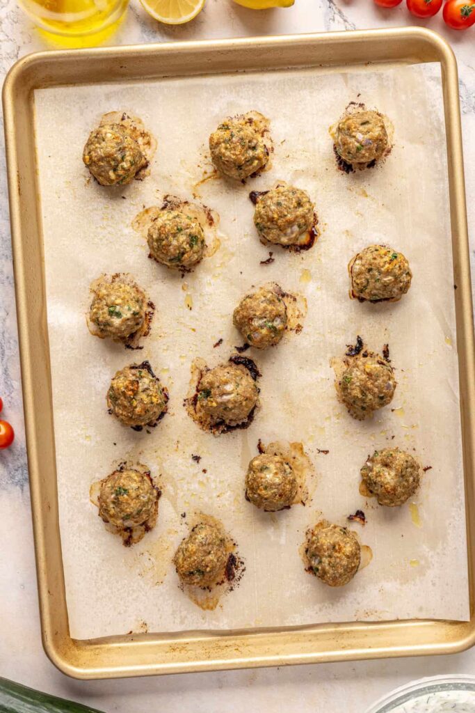 Tray of freshly baked Greek turkey meatballs seasoned with oregano and parsley.