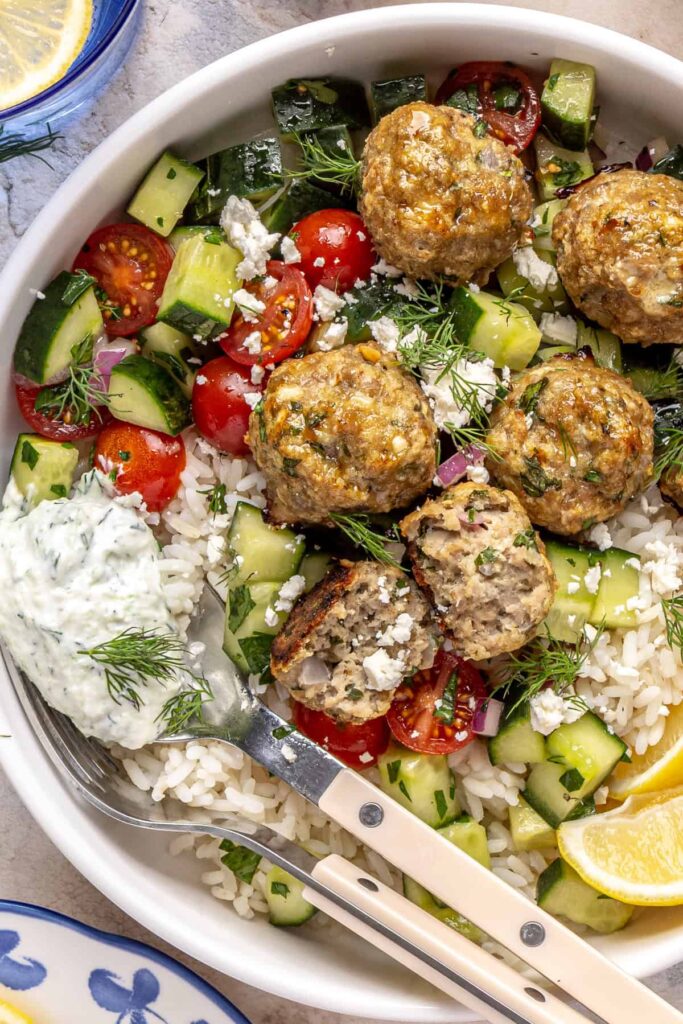 Juicy Greek turkey meatballs served over rice with tzatziki and cucumber-tomato salad.