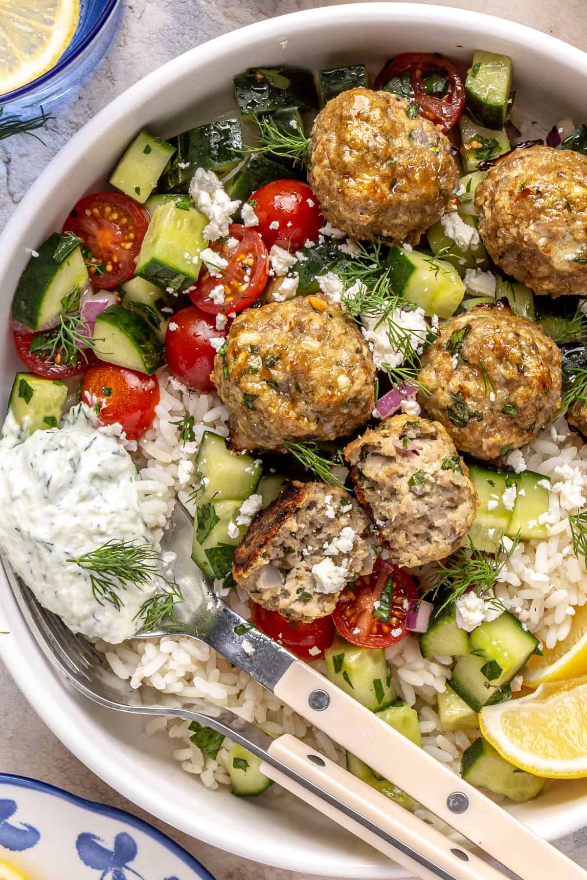 Juicy Greek turkey meatballs served over rice with tzatziki and cucumber-tomato salad.