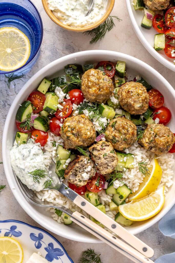 Juicy Greek turkey meatballs served over rice with tzatziki and cucumber-tomato salad.
