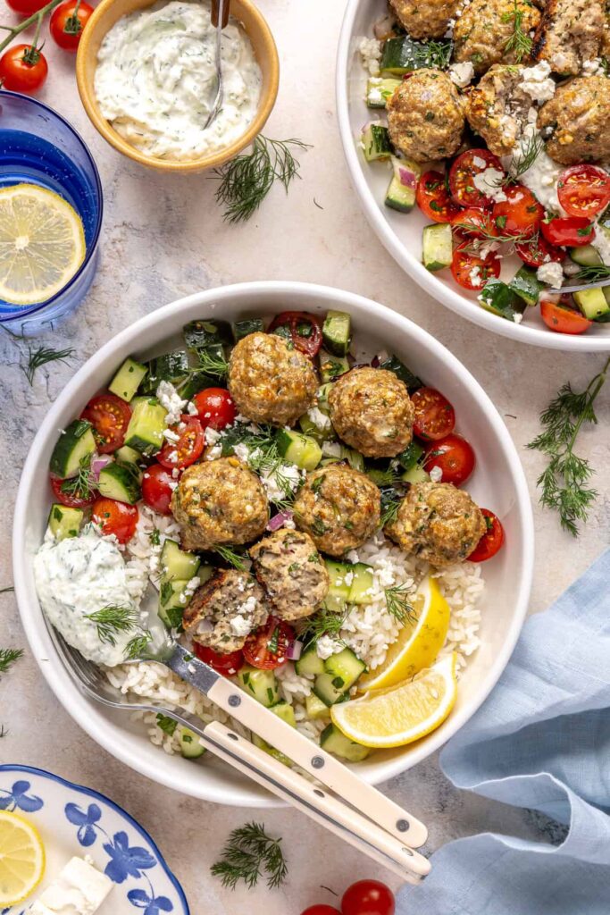 Greek turkey meatball bowl with rice, cucumber salad, and tzatziki.