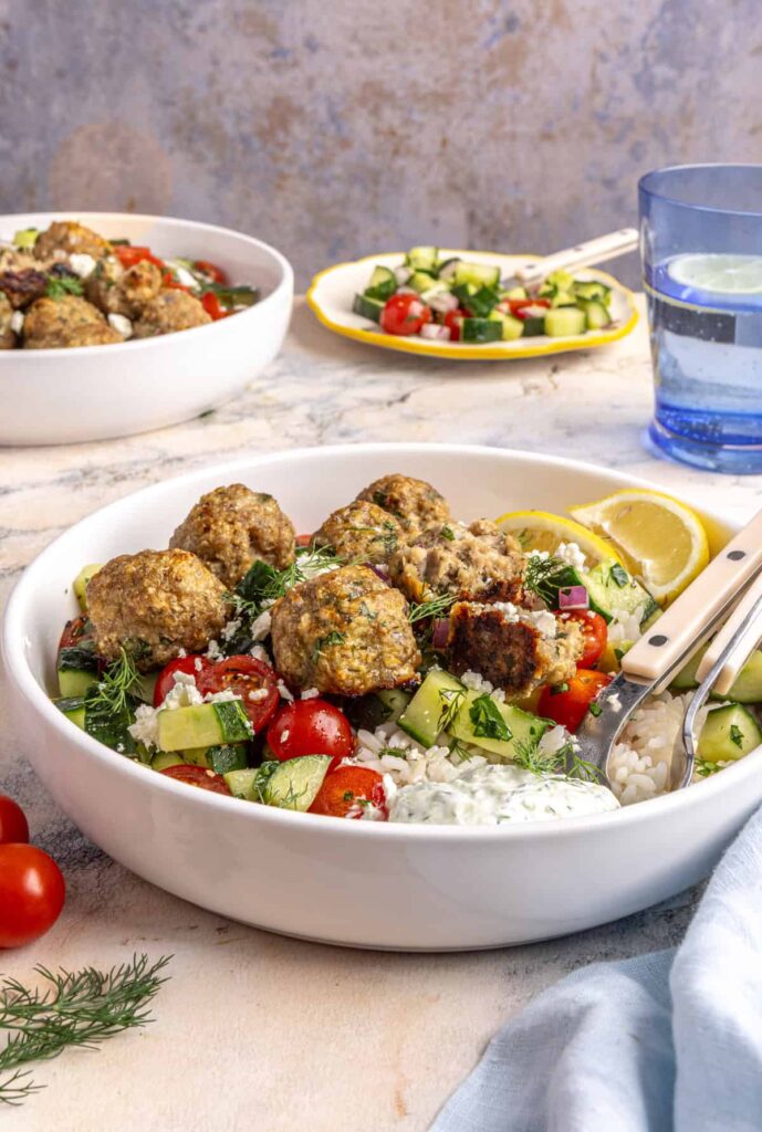 Juicy Greek turkey meatballs served over rice with tzatziki and cucumber-tomato salad.