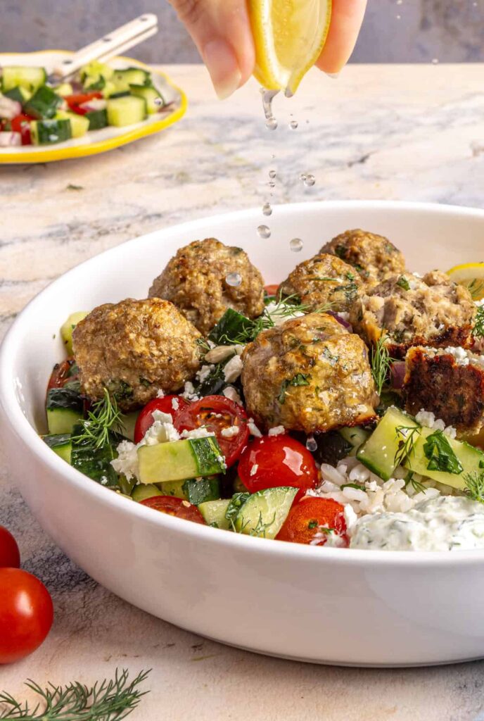 squeezing fresh lemon juice over juicy Greek turkey meatballs served over rice with tzatziki and cucumber-tomato salad.