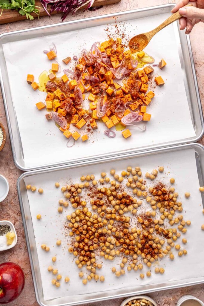 Harissa-seasoned sweet potatoes, shallots, and chickpeas on baking sheets for harvest salad