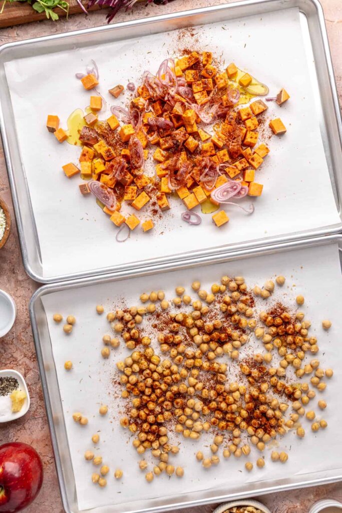 Harissa-seasoned sweet potatoes, shallots, and chickpeas on baking sheets for harvest salad