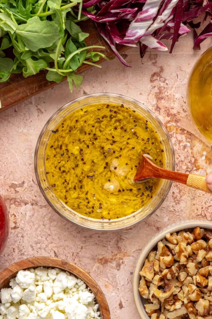Whisking tahini, lemon, garlic, and Dijon dressing for harvest salad