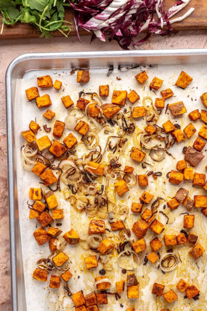 Diced sweet potatoes and shallots coated in harissa seasoning for harvest salad