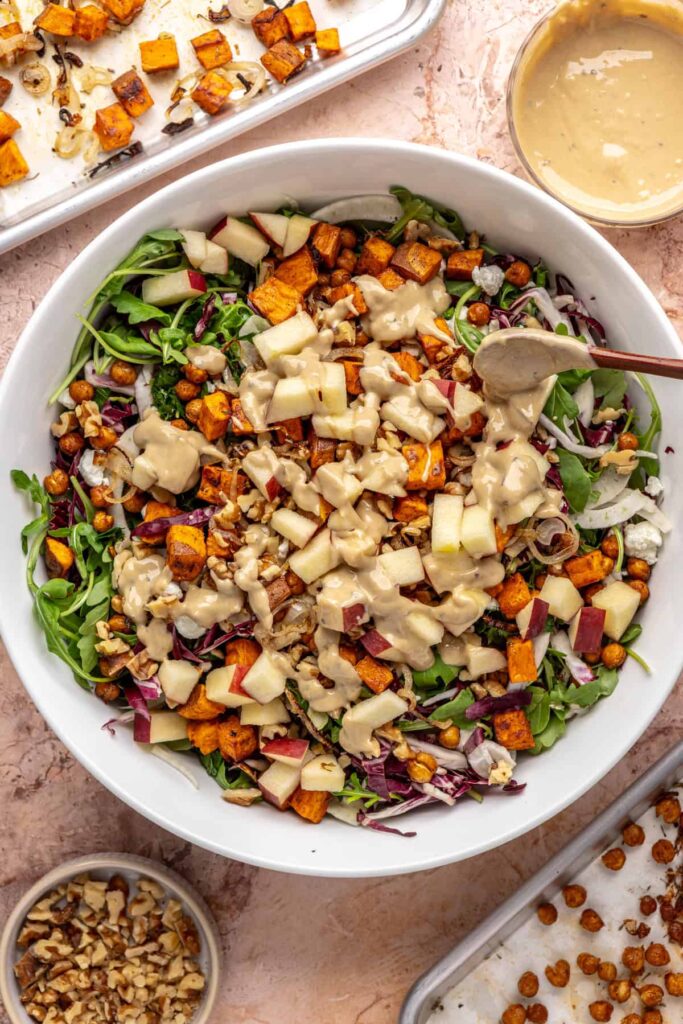 Adding tahini dressing to radicchio and frisée harvest salad