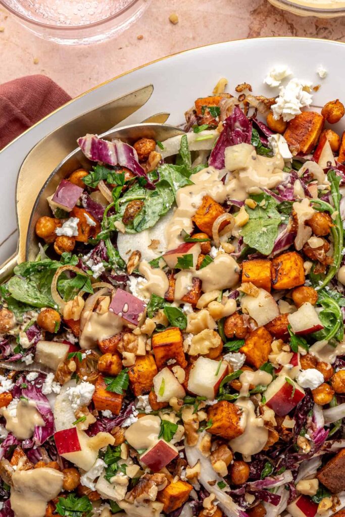 Fully assembled harvest salad topped with roasted vegetables and maple tahini dressing