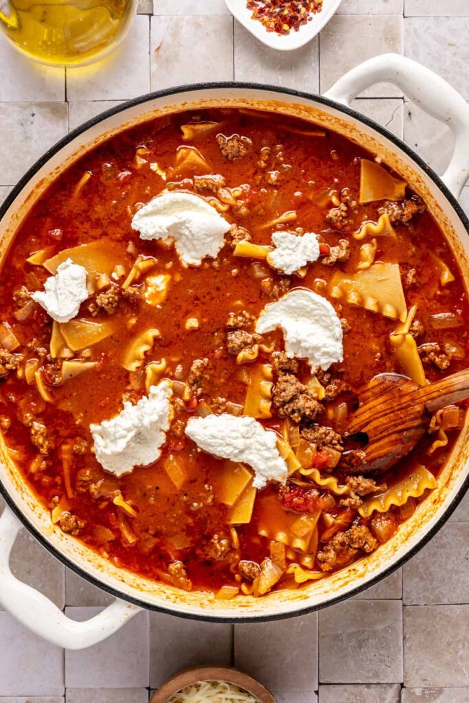 mixing a one-pot lasagna soup with dairy-free ricotta, ground beef, marinara, and gluten-free lasagna noodles.