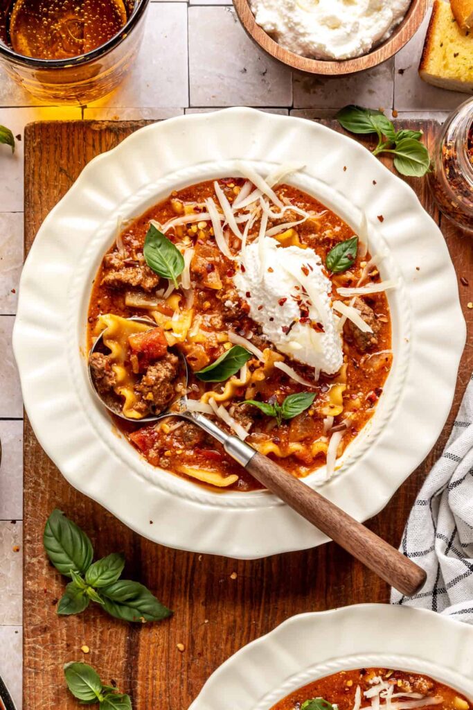High-protein lasagna soup in a bowl topped with dairy-free ricotta, basil, and chili flakes