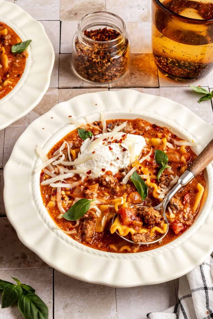 High-protein lasagna soup in a bowl topped with dairy-free ricotta, basil, and chili flakes