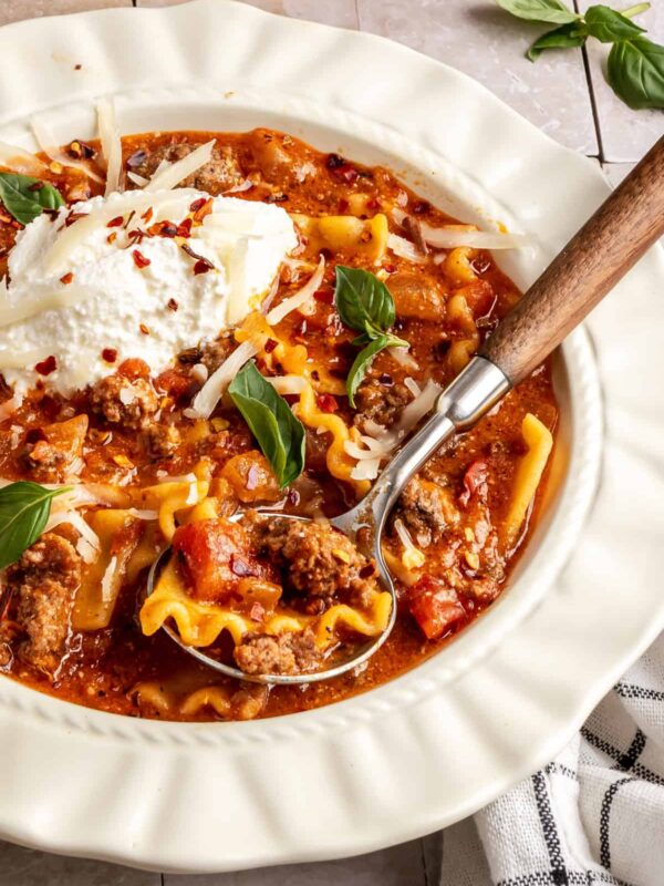 High-protein lasagna soup in a bowl topped with dairy-free ricotta, basil, and chili flakes