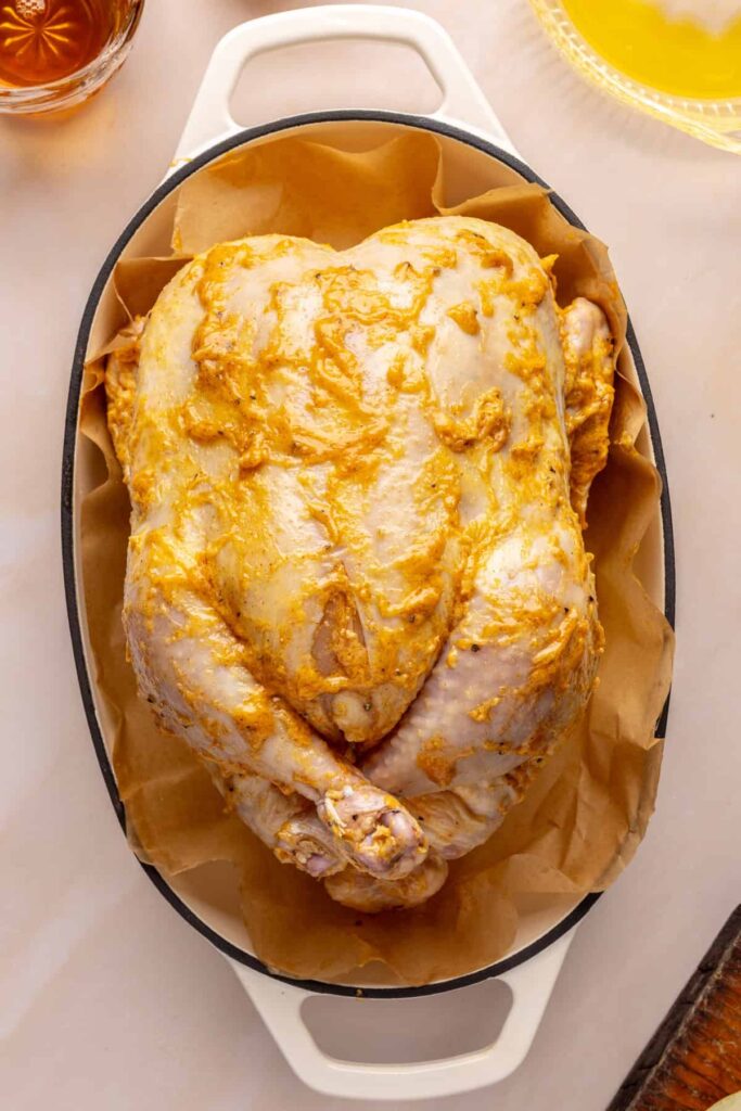 Whole Citrus Maple Chicken prepared in a roasting pan with garlic, onion, and fresh herbs