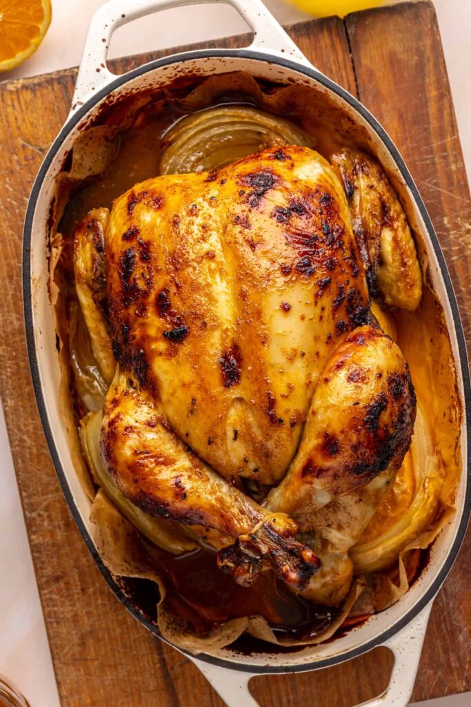 Finished Citrus Maple Chicken in a roasting pan with garlic, onion, and fresh herbs