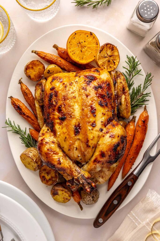 overhead shot of Citrus Maple Chicken served on a plate with roasted carrots, potatoes, and fresh herbs