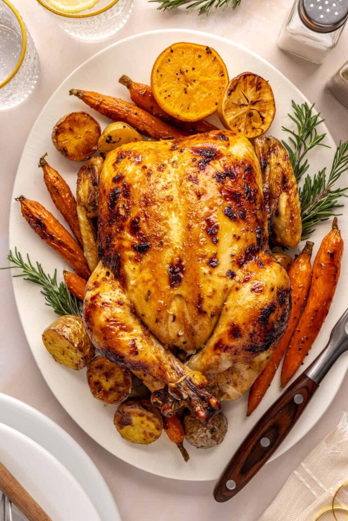 Citrus Maple Chicken served on a plate with roasted carrots, potatoes, and fresh herbs