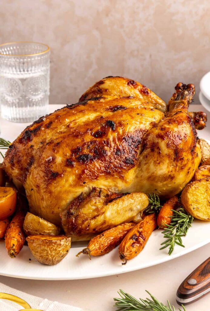 Golden Citrus Maple Chicken on a serving plate with roasted carrots, potatoes, and rosemary