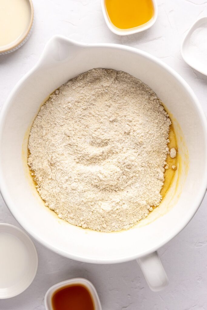 dry ingredients poured on top of wet ingredients in a bowl for gluten-free Christmas Sugar Cookies