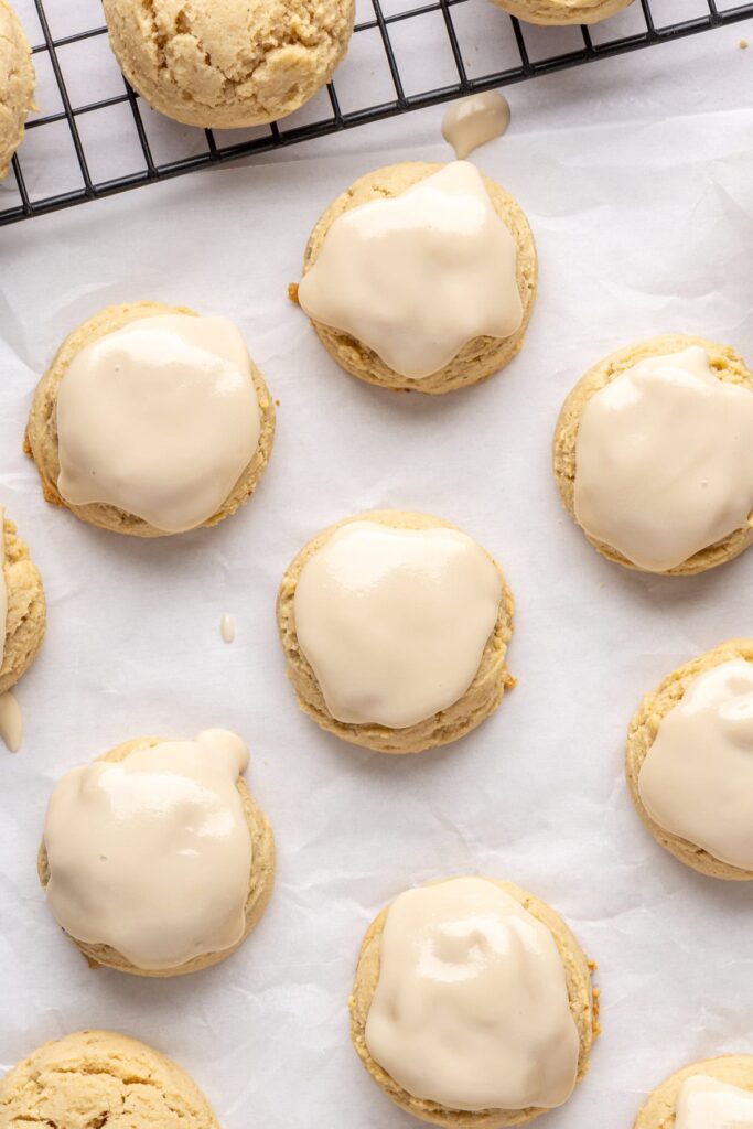 close-up of iced Christmas Sugar Cookies on parchment paper and a baking sheet