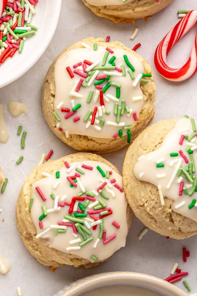 close-up of Gluten-free Christmas sugar cookies with creamy frosting and festive sprinkles on a styled baking sheet