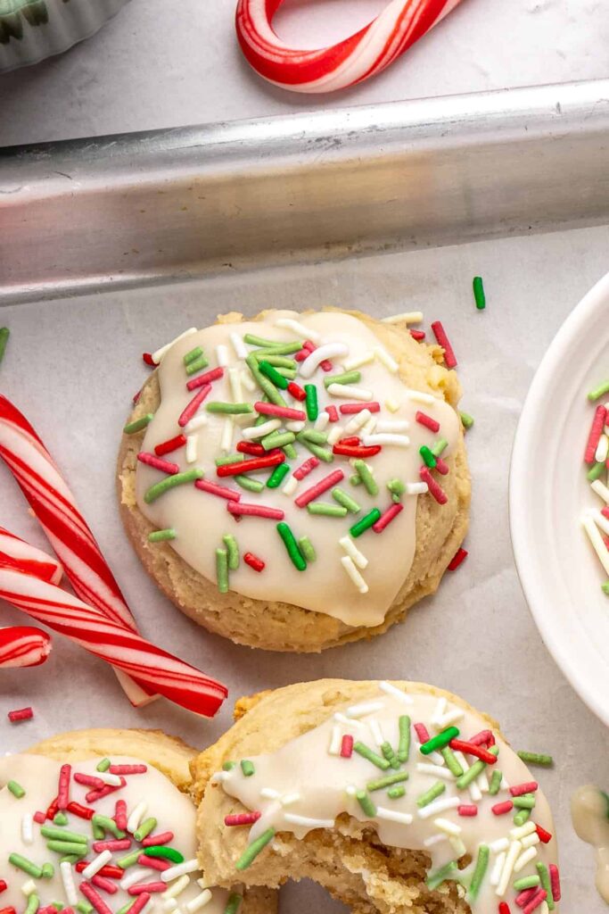 close-up of Gluten-free Christmas sugar cookies with creamy frosting and festive sprinkles on a styled baking sheet