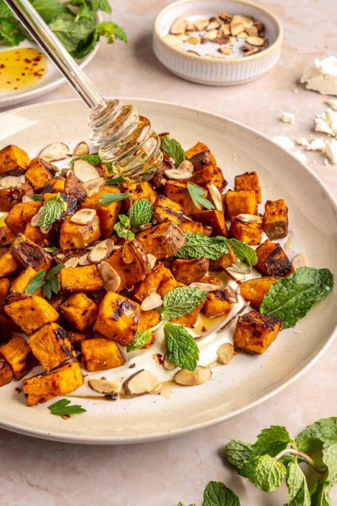Drizzling hot honey over roasted sweet potatoes with whipped feta and fresh herbs