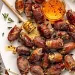 Holiday appetizer: prosciutto wrapped stuffed dates with goat cheese and hot honey on platter with honey dipper