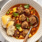 Close-up of tender beef meatballs and vegetables in savory meatball soup garnished with parsley