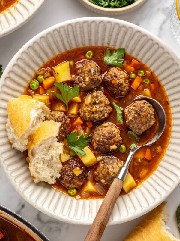 Close-up of tender beef meatballs and vegetables in savory meatball soup garnished with parsley