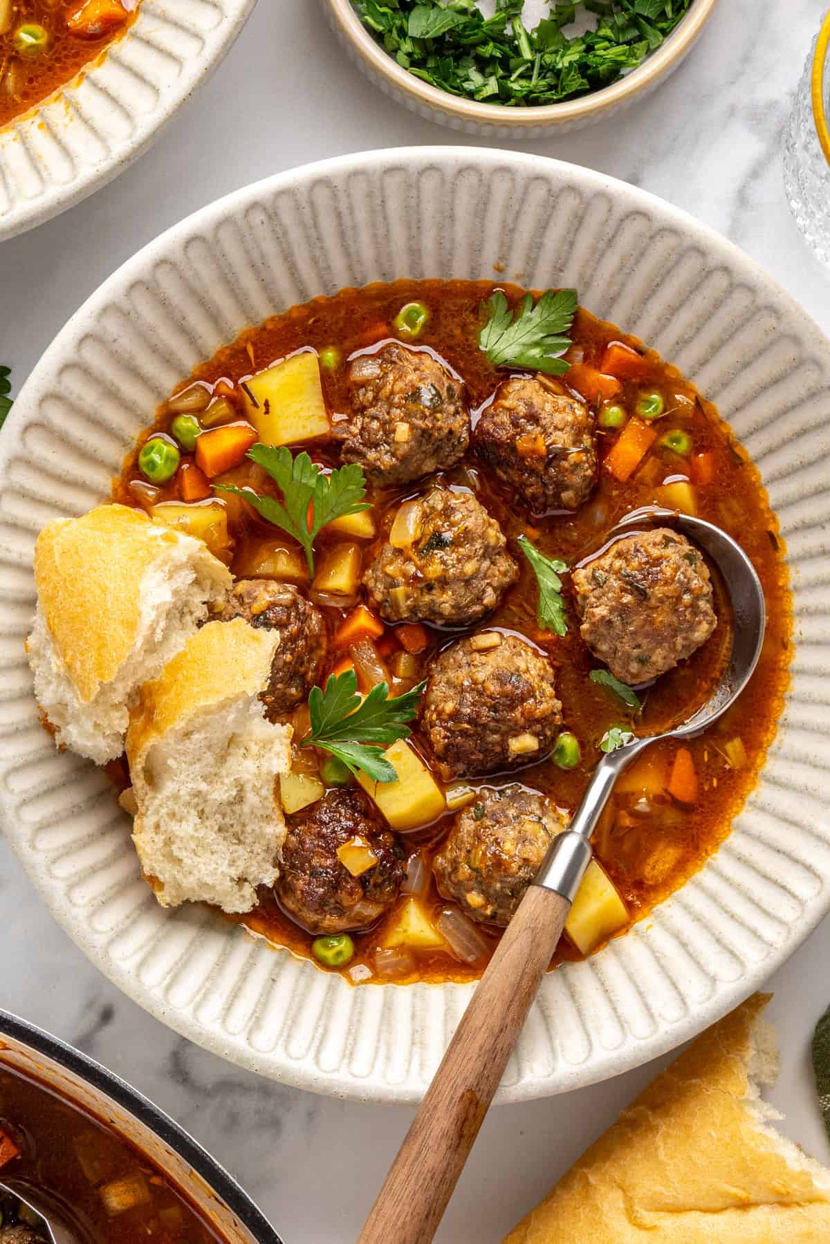 Close-up of tender beef meatballs and vegetables in savory meatball soup garnished with parsley