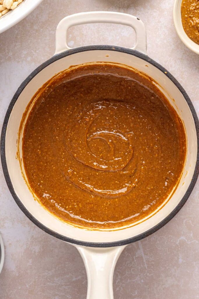 Melted mixture of peanut butter, maple syrup, coconut sugar, coconut oil, and salt in a pot for salted peanut butter bars.