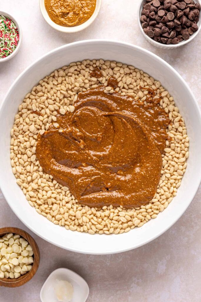 Pouring peanut butter mixture over brown rice cereal to make salted peanut butter bars base.