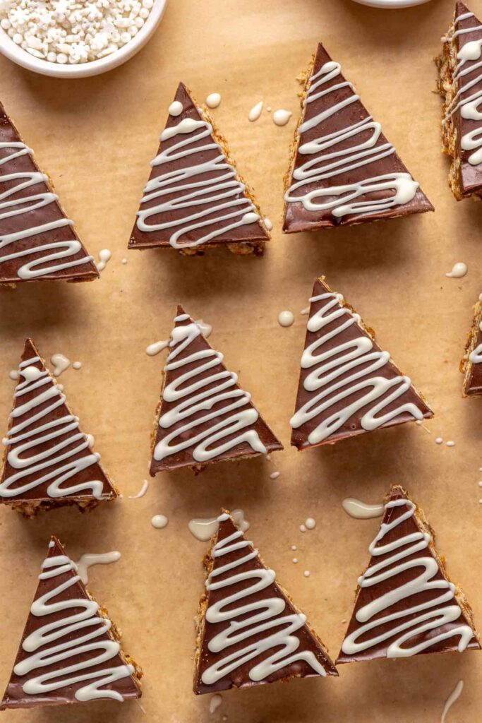 Drizzling melted white chocolate over salted peanut butter bars triangles for decoration.