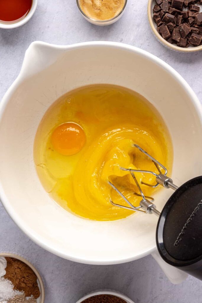 Mixing eggs and avocado oil until pale and fluffy for the pumpkin spice chocolate loaf batter.