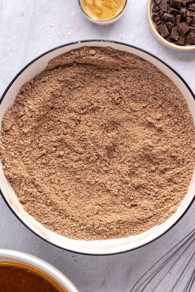 Dry ingredients for pumpkin spice chocolate loaf, including almond flour, cacao, and pumpkin spice, combined in a bowl, ready to have the wet ingredients added