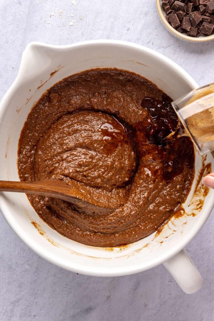 pouring the hot espresso shot into the bowl while combining dry and wet ingredients to form the pumpkin spice chocolate loaf batter.