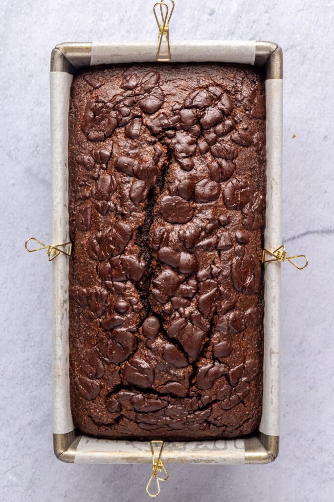 Pumpkin spice chocolate loaf fresh out of the oven in the loaf pan, cooling before slicing.