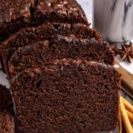 Pumpkin spice chocolate loaf slice on a plate with cloves and a cinnamon stick, gluten-free and dairy-free.