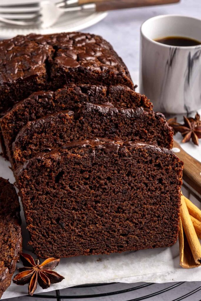 Pumpkin spice chocolate loaf slice on a plate with cloves and a cinnamon stick, gluten-free and dairy-free.