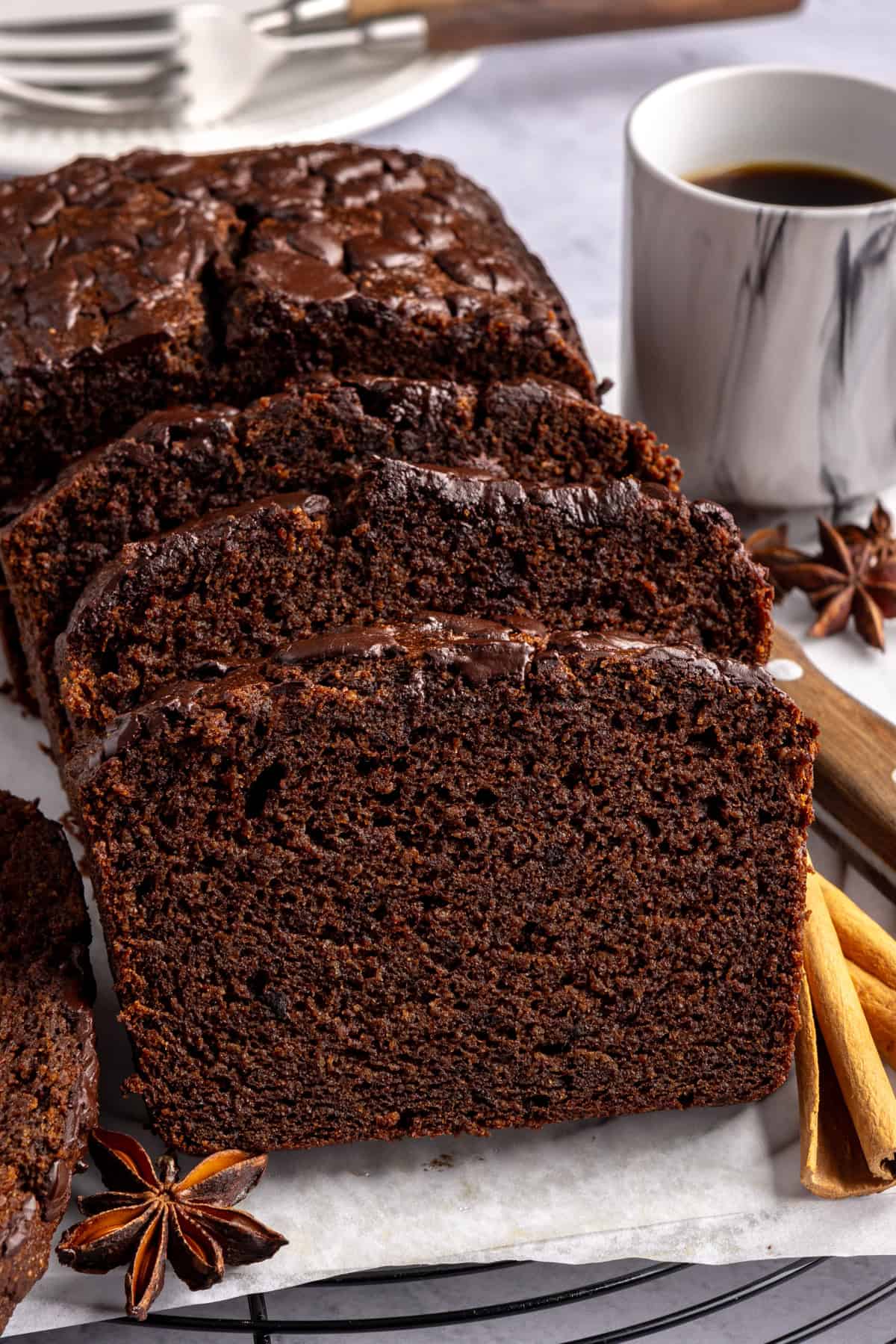 Pumpkin spice chocolate loaf slice on a plate with cloves and a cinnamon stick, gluten-free and dairy-free.