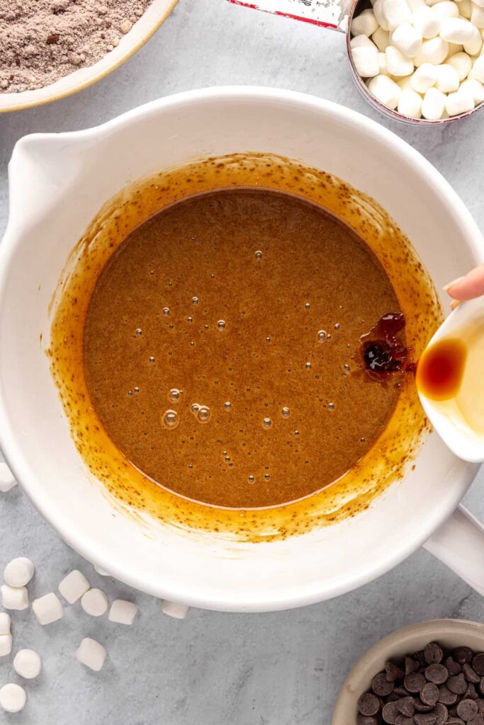 pouring the vanilla extract into the whisked wet ingredients for hot cocoa cookies