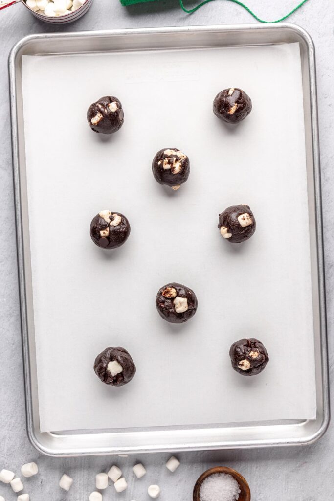 Preparing hot cocoa cookies for the oven with marshmallow topping