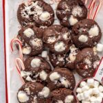 Holiday hot cocoa cookies arranged with candy canes on a festive tray