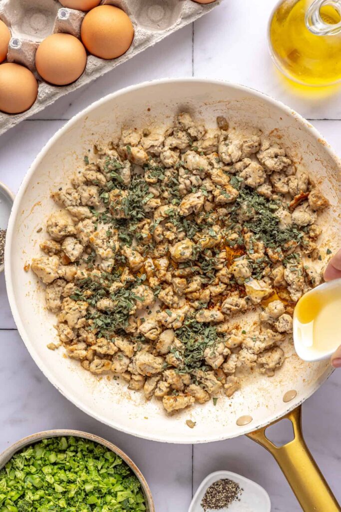 pouring the maple syrup into the Golden, crispy maple sage chicken sausage in skillet for egg bake